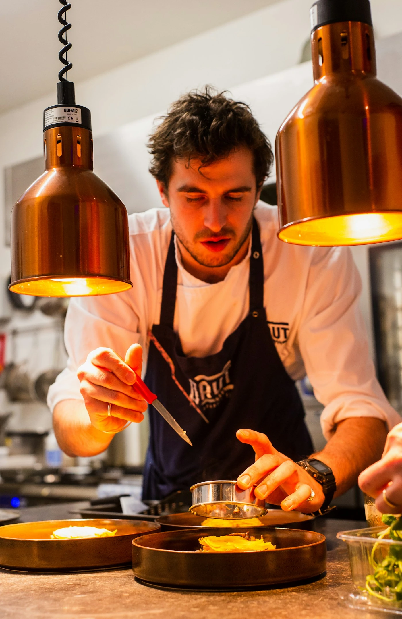 Chef carefully plating a meal under warm kitchen lights